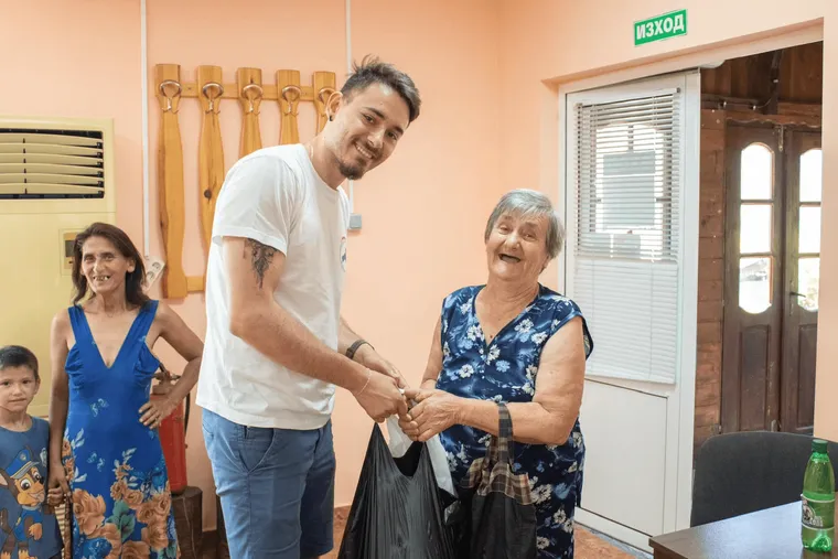 Доброволец предава хранителен пакет на възрастна жена